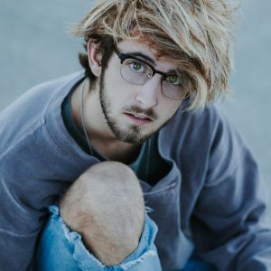 a young man with a messy haircut and glasses